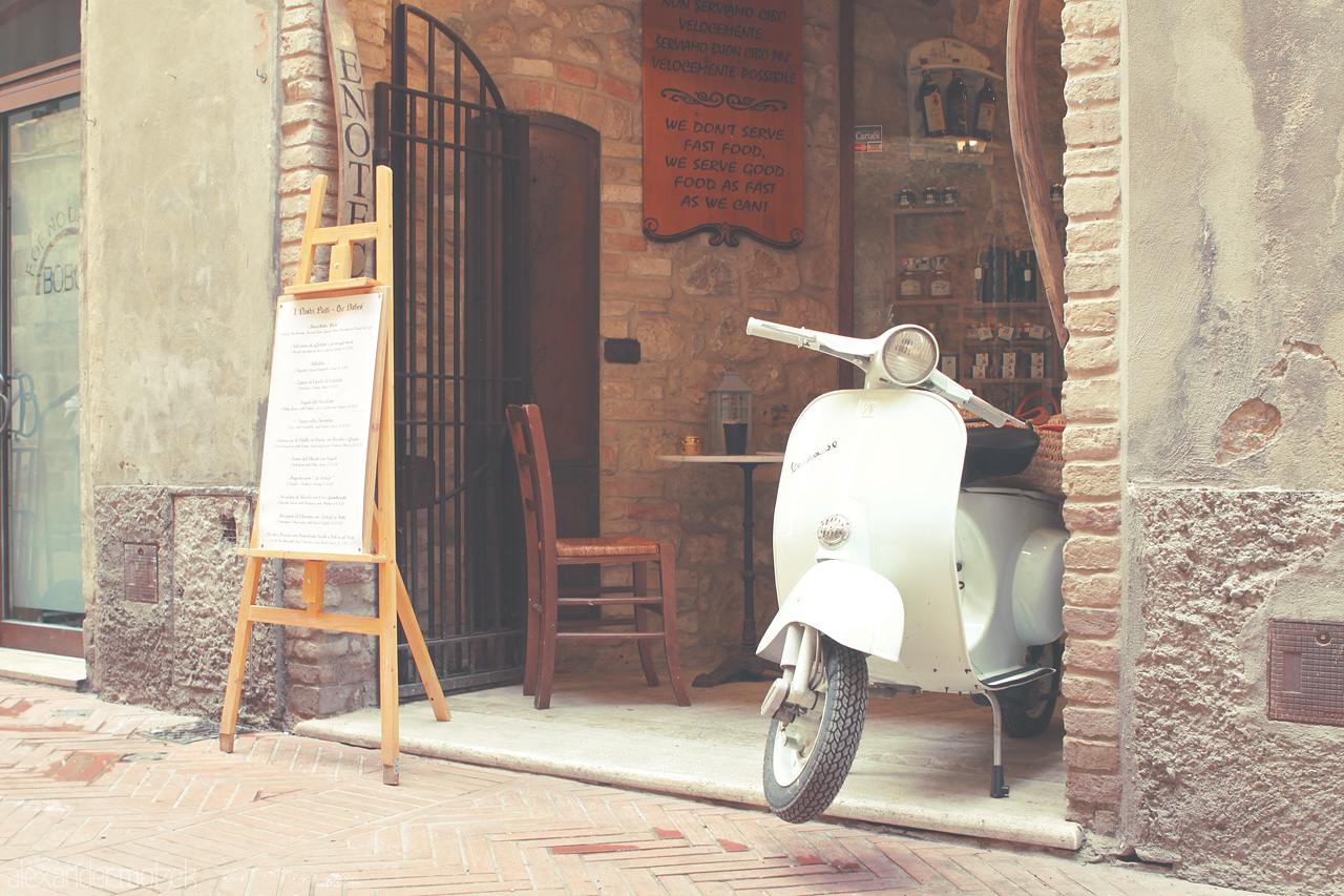 Vespa Tranquillità Foto von A charming Vespa rests at a rustic café in the heart of Tuscany, exuding an air of timeless Italian allure.
