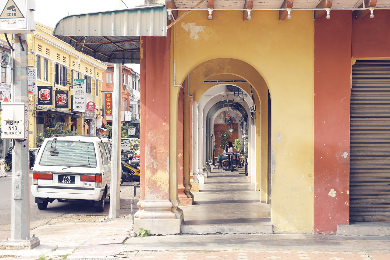 Foto von A colorful colonial arcade in Penang showcases vibrant arches and a bustling street life. A serene glimpse into Penang's heritage charm.
