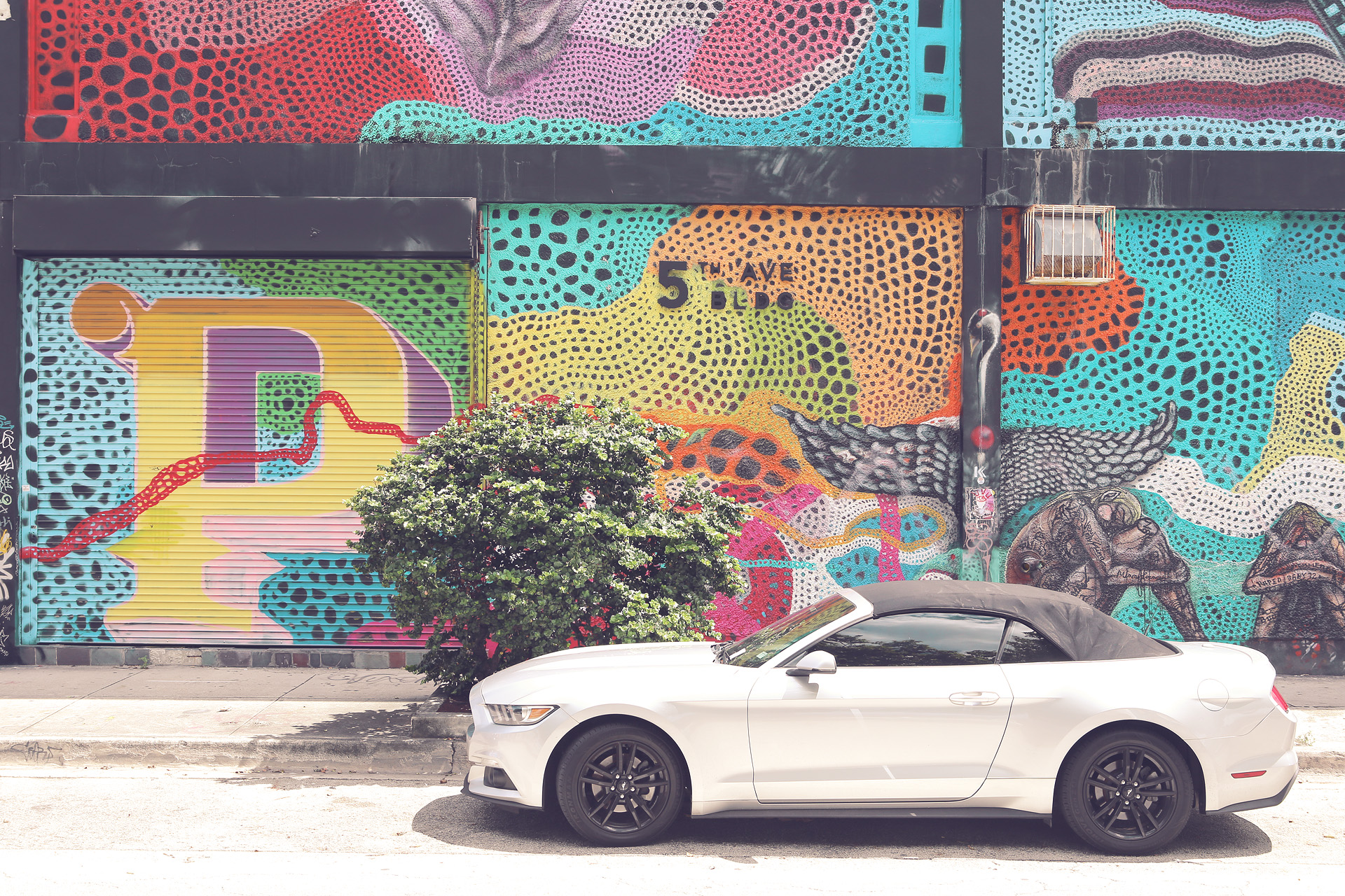 Miami Mosaic Magic Foto von A contemporary convertible parked against Miami's colorful street art, capturing the city's vibrant and eclectic spirit on 5th Ave.