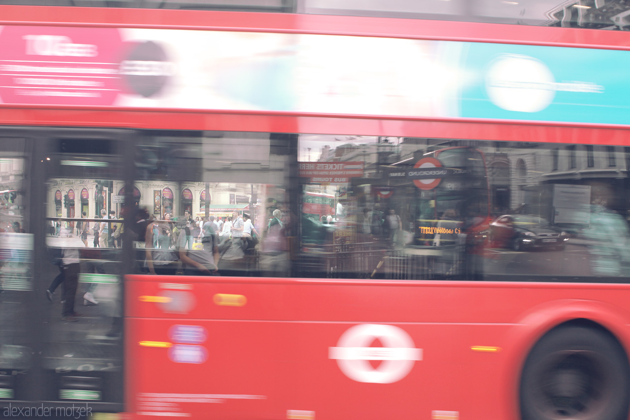 London's Whirlwind Foto von A dynamic capture of a classic London red bus in motion, blurring past iconic city streets.
