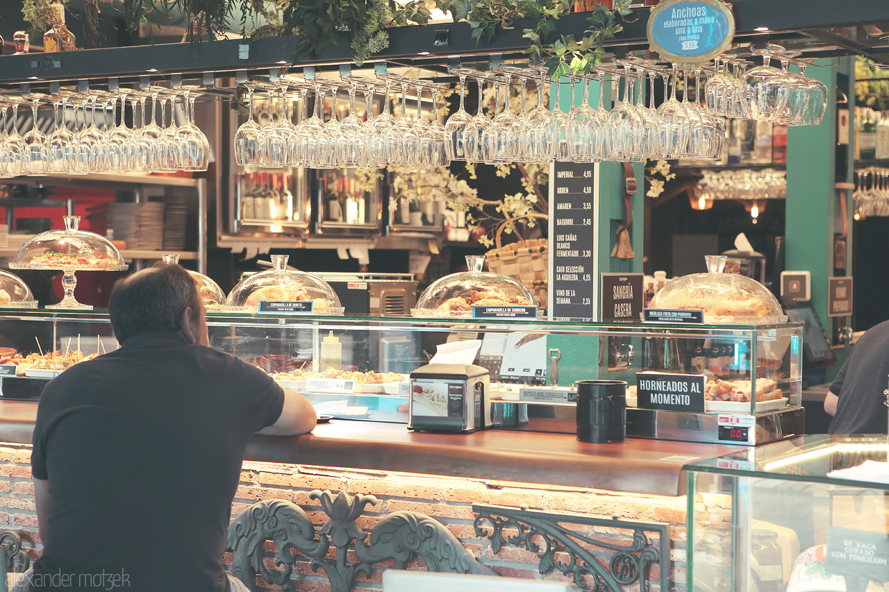 Pintxos Pause Foto von A local gazes at a bar's tapas selection under glinting rows of glassware in Bilbao, Spain.