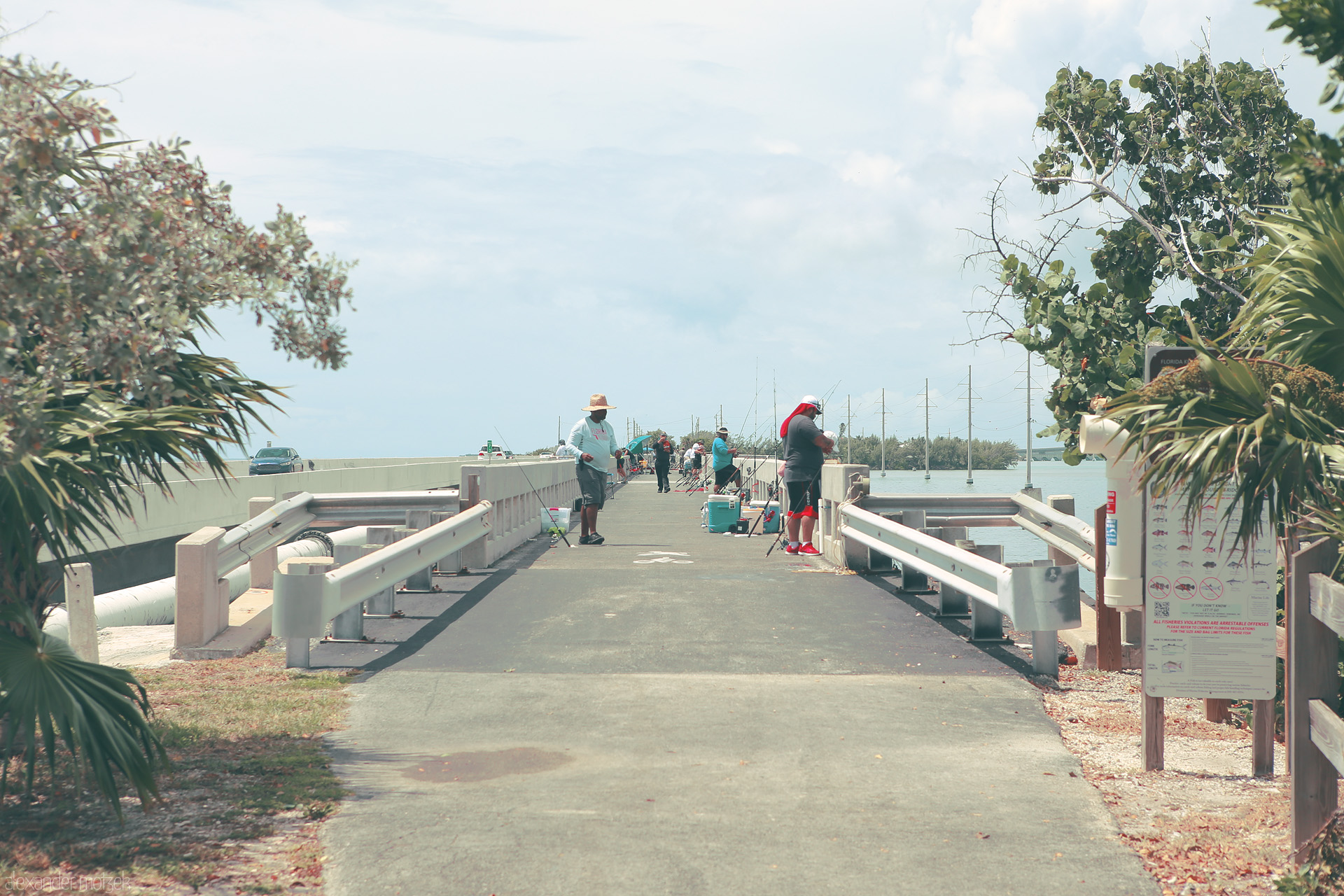 Keys Tranquility Foto von A peaceful scene on a bridge in Monroe County, Florida. Fishermen line the path under cloudy skies and lush palms.