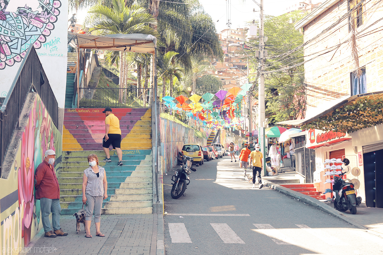Colores de Comuna 13 Foto von A snapshot of Comuna 13, Medellín showcasing vibrant street art, colorful flags, and local life amidst bustling streets.