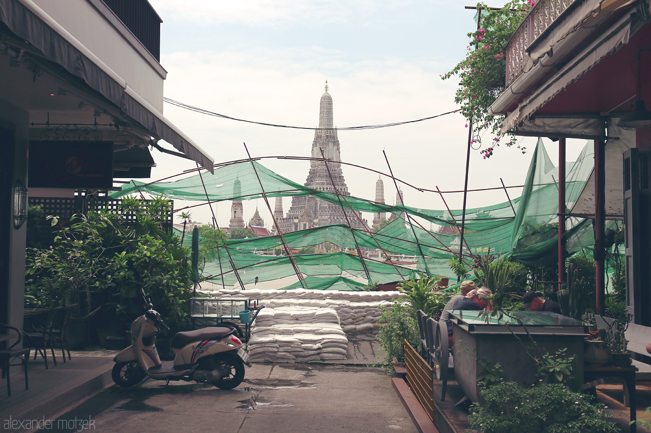 Wat Arun Vista Foto von A street view in Phra Borom Maha Ratchawang, Bangkok, with Wat Arun rising in harmony amid urban life and lush greenery.