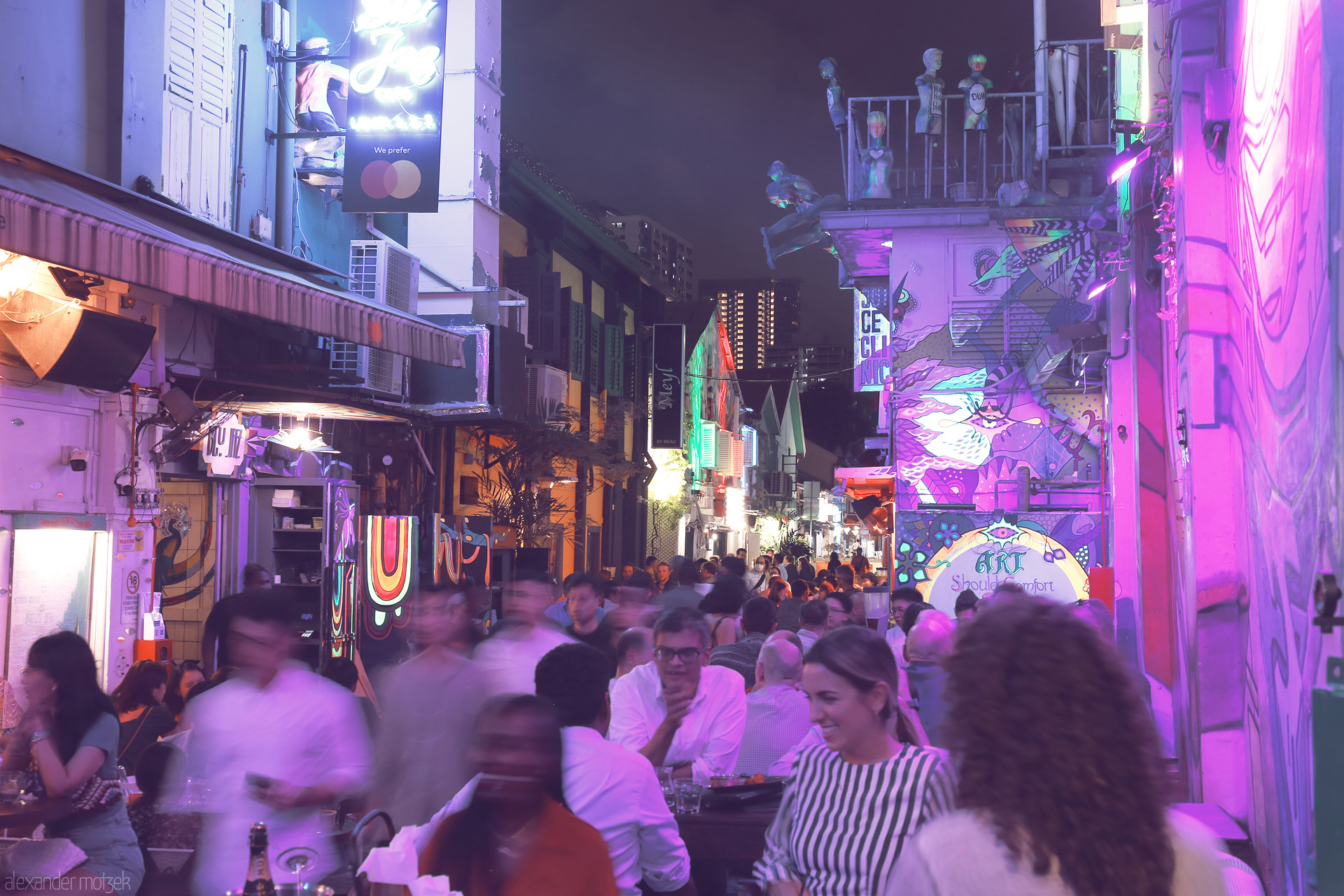 Foto von A vibrant, neon-lit alley in Singapore’s Bugis district, crowded with locals and travelers sharing food, art, and laughter under urban nights.