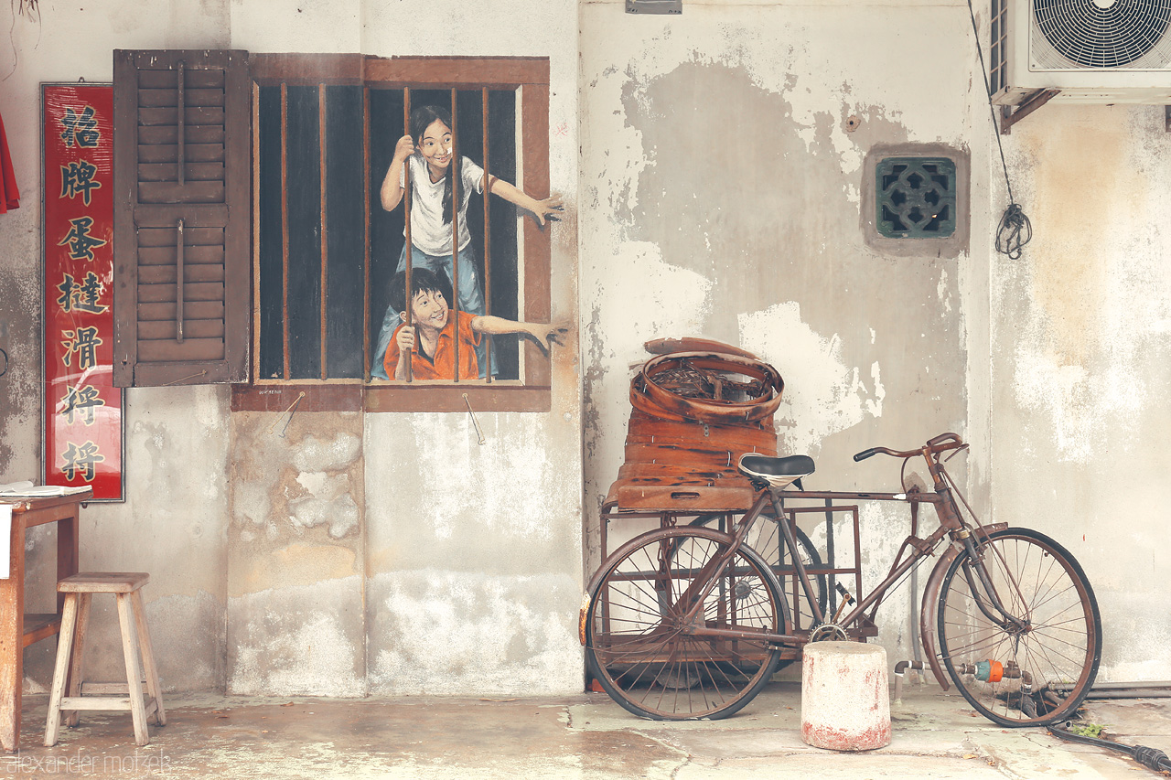 Whiskers of Time Foto von A whimsical street mural in Penang depicts children at play beside an old bicycle, capturing the spirit of Georgetown's vibrant cultural art scene.