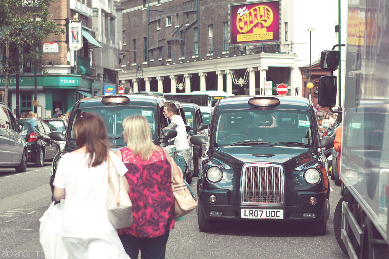 London's Urban Ballet Foto von Black cabs and bustling pedestrians define a lively street scene in Camden, London, encapsulating the city's vibrant urban life.