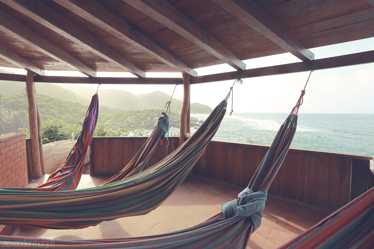 Sueños en Tayrona Foto von Colorful hammocks sway gently under a wooden roof, overlooking the pristine coastline of Tayrona, Santa Marta, Colombia.