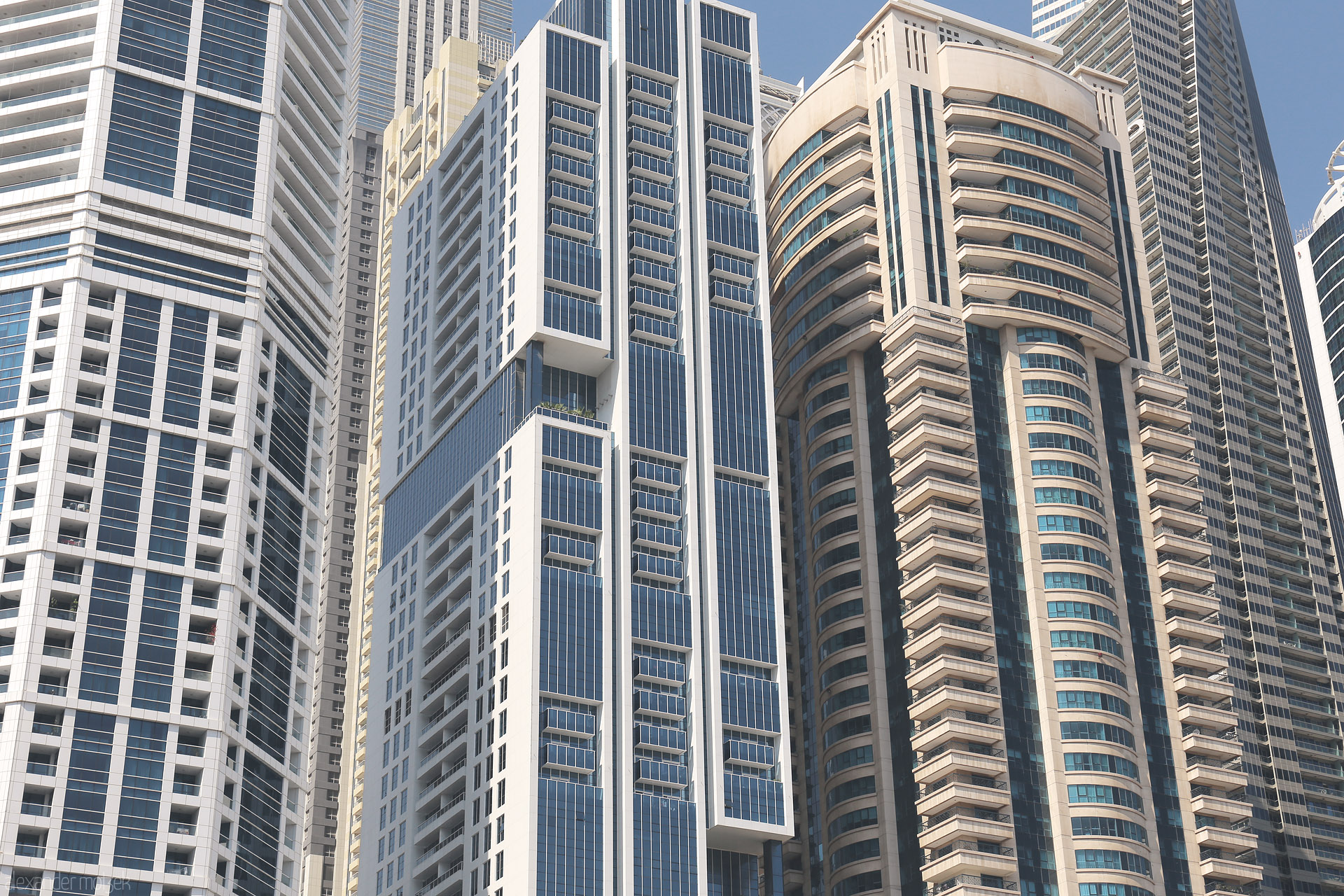 Vertical Oasis Foto von Soaring modern towers in Dubai's Marina, a geometric dance of sunlit glass and steel against the cloudless desert sky.