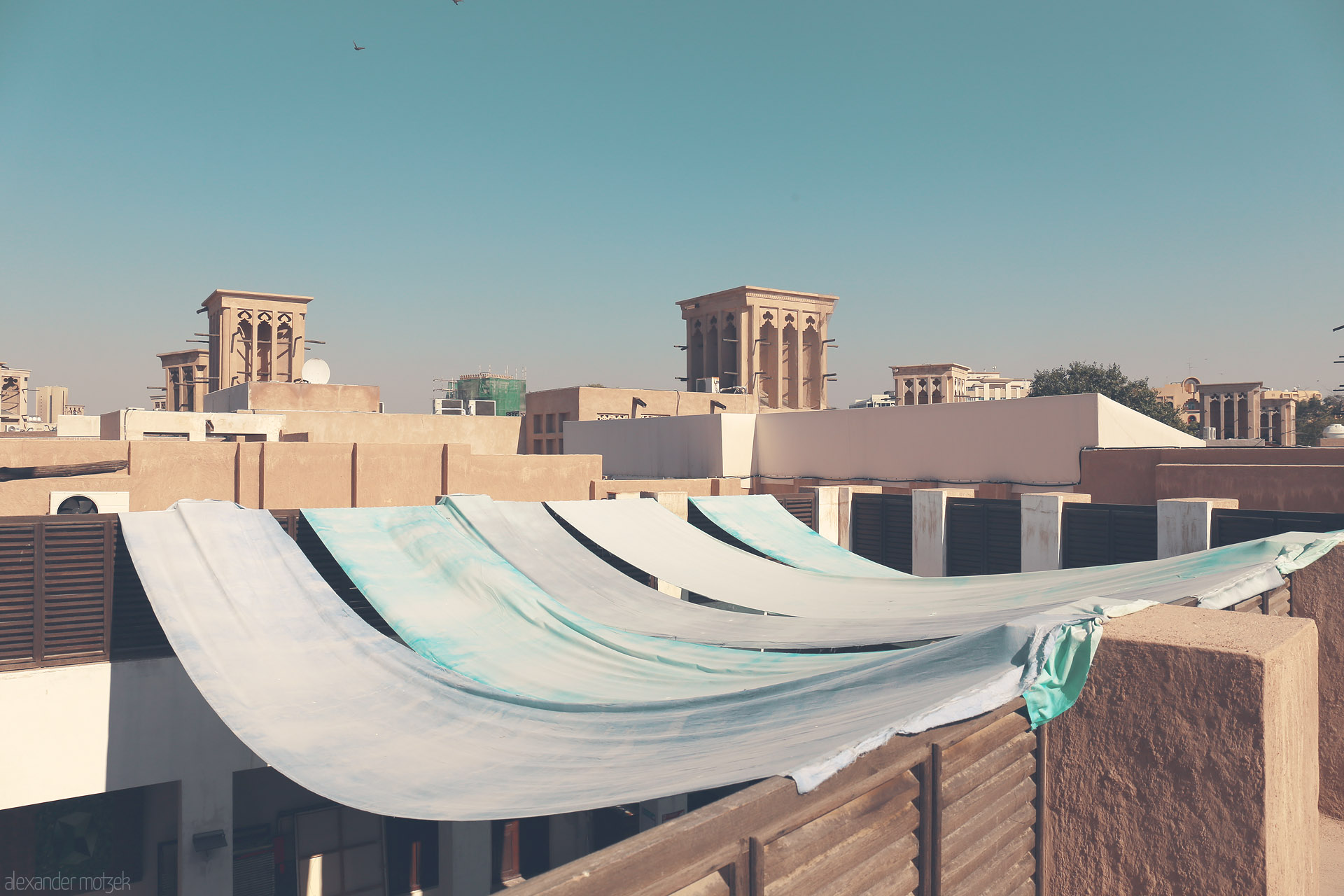 Foto von Soft fabrics dance over Al Fahidi's wind towers, blending tradition and sun in the historic heart of Dubai, UAE.