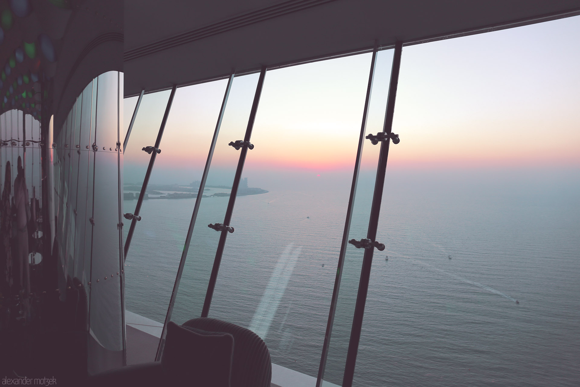 Ayn Dubai Horizon Foto von Through Burj Al Arab’s glass, Dubai’s coast glows at sunset—modern luxury meeting the tranquil Persian Gulf.