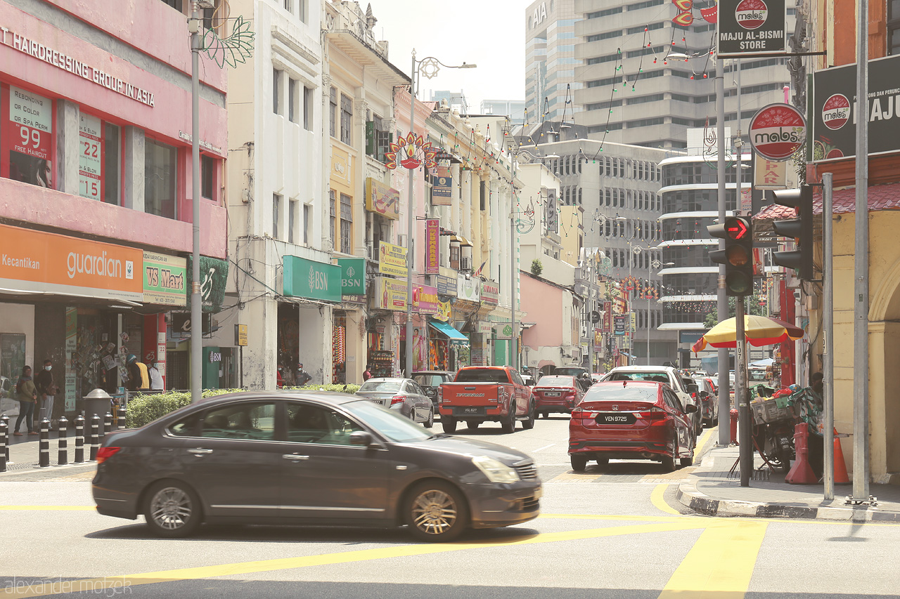 Kuala Pulse Foto von The vibrant hustle of Kuala Lumpur's streets, blending culture and modernity, with colorful storefronts and bustling traffic.