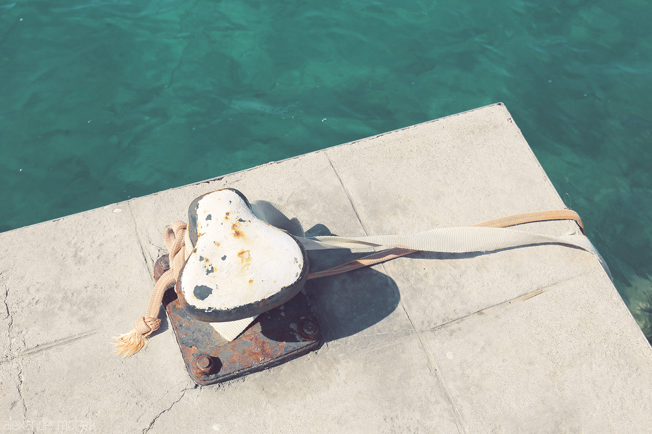 Foto von A weathered mooring bollard with a rope on Andratx's serene waterfront, embodying Mallorca's maritime spirit.