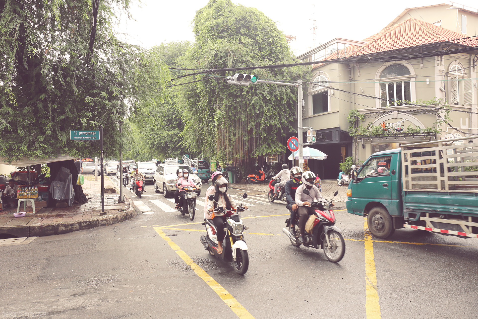 Foto von Morning buzz at Preah Ang Yukanthor St, Phnom Penh — scooters, street eats, and lush greenery in a uniquely Cambodian dance.