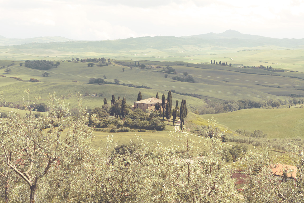 Dolce Vita Vista Foto von Rolling hills of Tuscany embrace a secluded villa, framed by iconic cypress trees under an expansive sky.