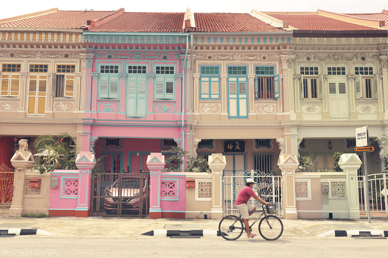 Pastel Peranakan Dream Foto von A cyclist passes iconic pastel-colored Peranakan houses in the vibrant Joo Chiat neighborhood, Singapore.
