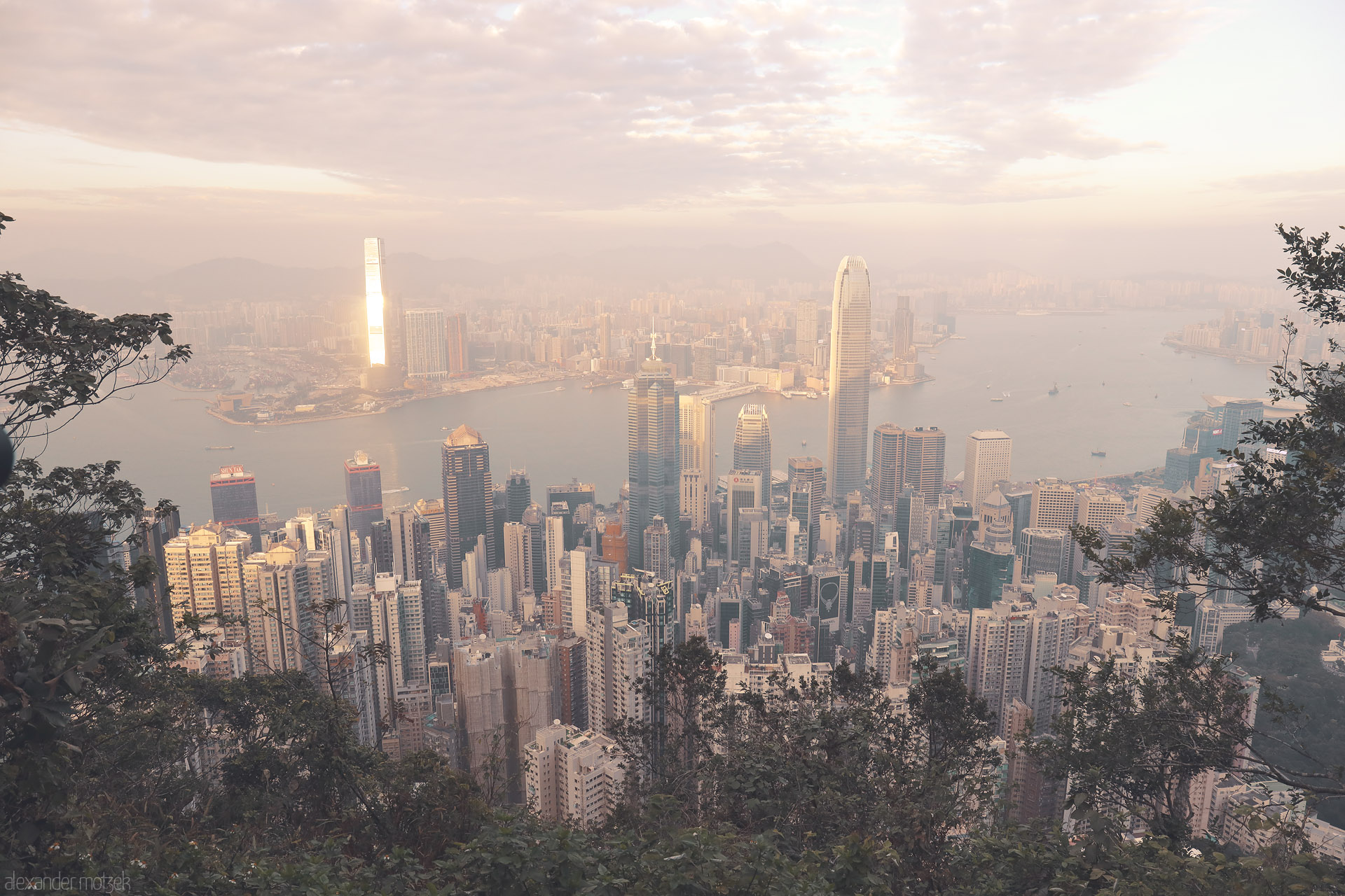 Foto von Sunlit haze over Central’s skyscrapers and Victoria Harbour, viewed from Victoria Peak on Hong Kong Island, Hong Kong.