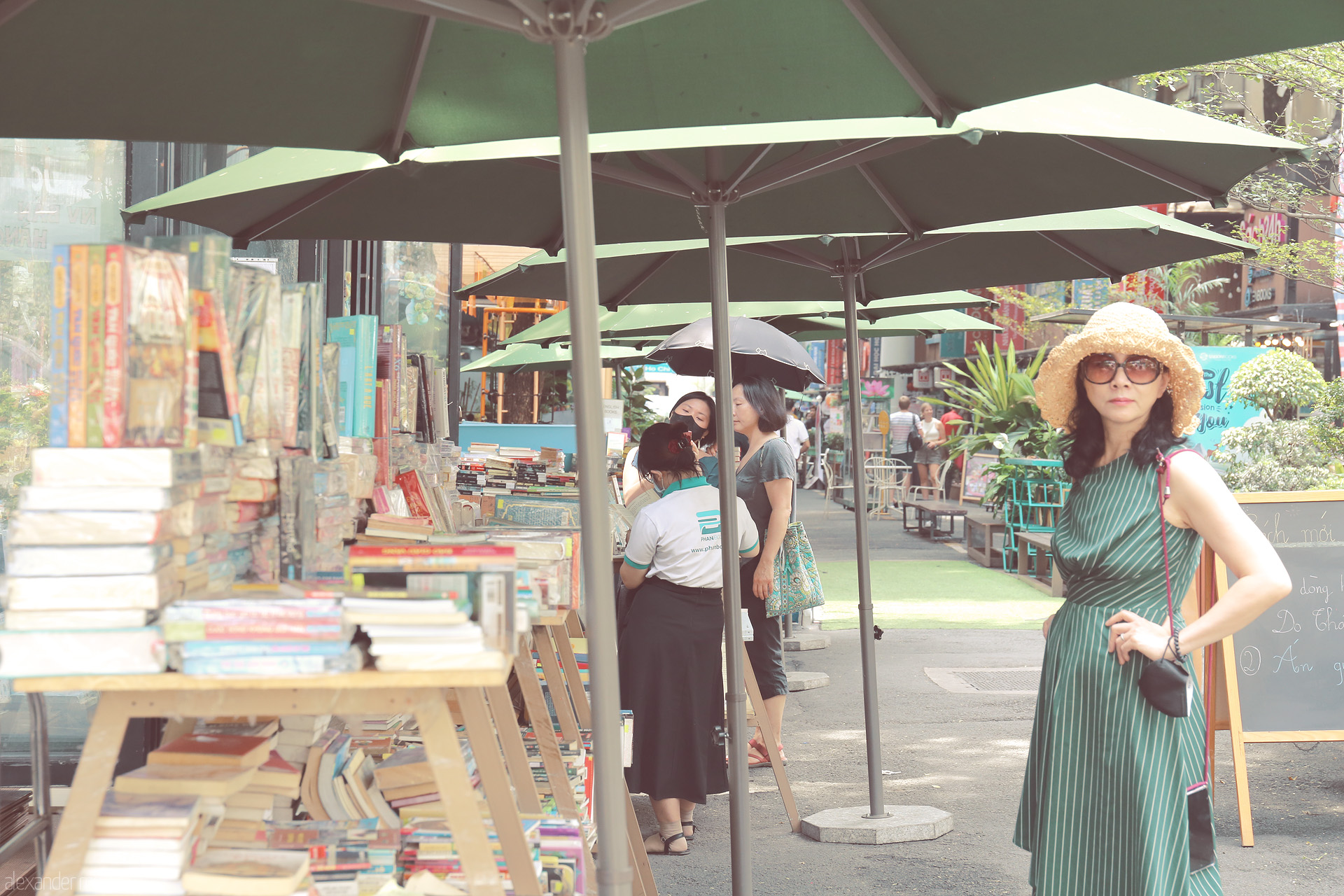 Foto von Under green umbrellas on Saigon’s Book Street, a woman in sunglasses captures the spirit of literary HCMC. Vietnam vibrance, sun, and stories.