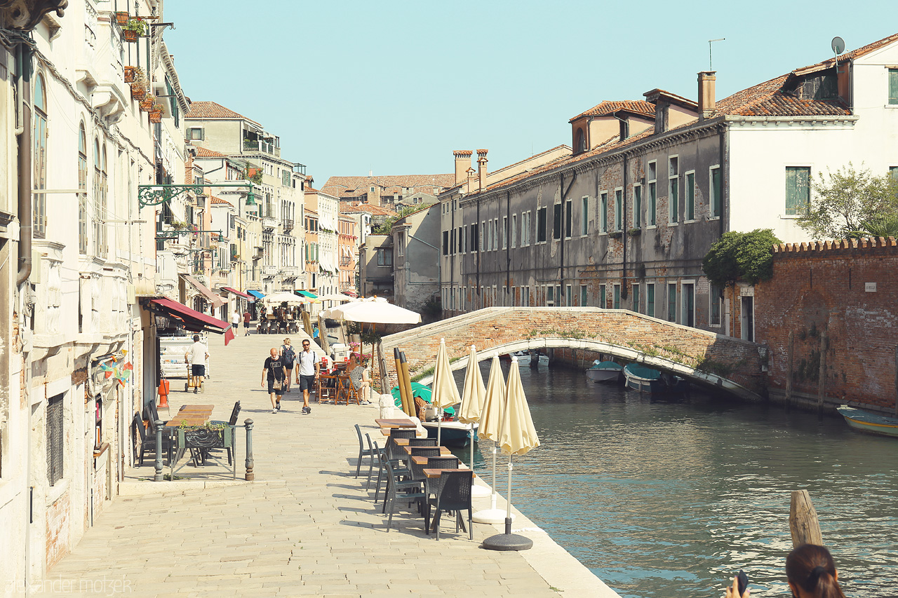 Sospiri Veneziani Foto von Sunny day in Venice with a quaint bridge and historic buildings lining a tranquil canal.