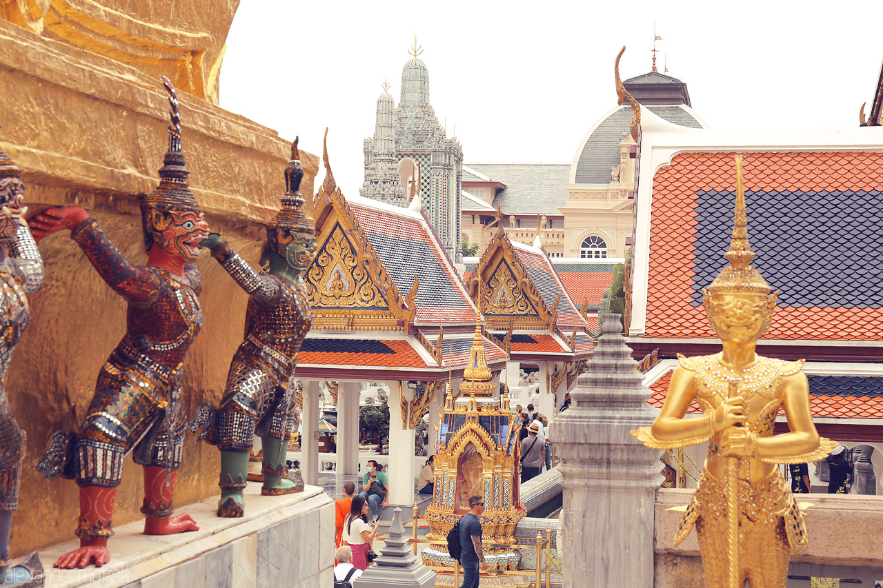 Golden Guardians Foto von Vibrant guardians and ornate roofs dazzle at Phra Borom Maha Ratchawang, Bangkok. A feast of traditional Thai architecture.