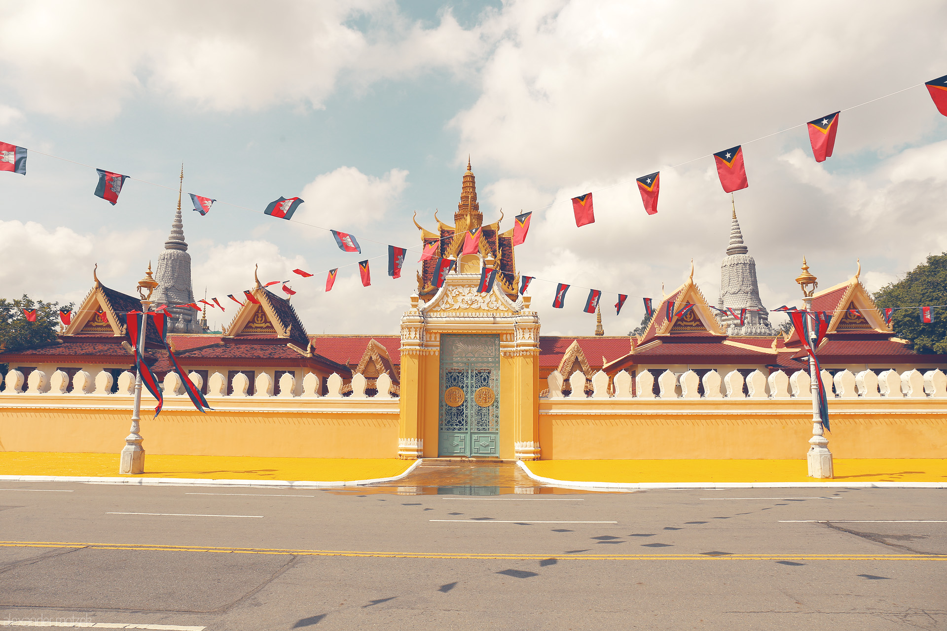Foto von Vivid yellow gates and fluttering Khmer flags guard the ornate Royal Palace under Phnom Penh’s sunlit skies.